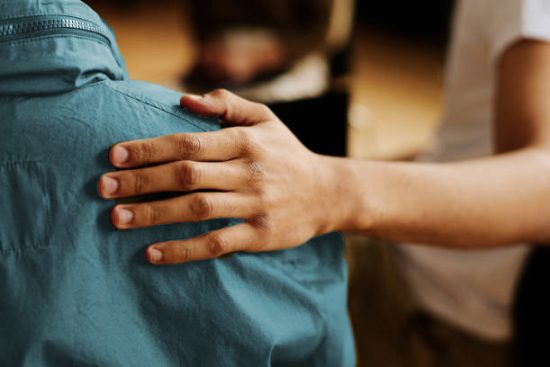 Hand of young supportive man consoling his friend or one of attendants with post traumatic syndrome caused by dramatic life event